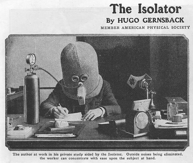 A black and white photograph from a magazine showing someone from the early 20th century wearing "The Isolator", a full head helmet with two eye holes and oxygen tube, making it look like a deep sea helmet. The person is sitting at a writing desk, working diligently (one presumes) on their grant proposal.