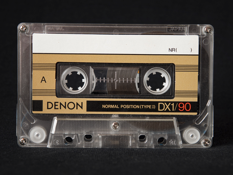An audio cassette. A rectangular semitransparent case with two toothed wheels with black audio tape wound around each of them. On the tape is the trapped soul of many small screaming demons that shout into a small microphone as the tape is passed from one reel to another.